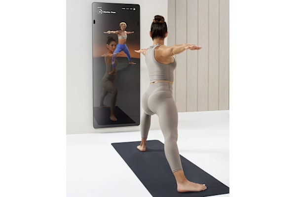 a woman standing in front of a mirror doing a yoga pose with her arms out